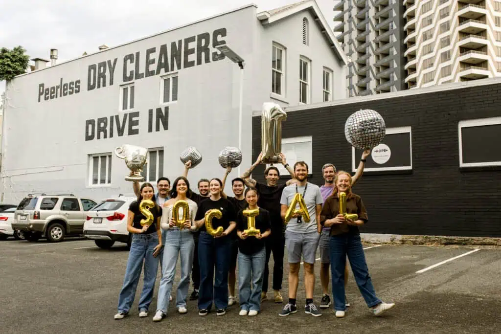 Excite Media team holding gold foil balloons that spell 'social'