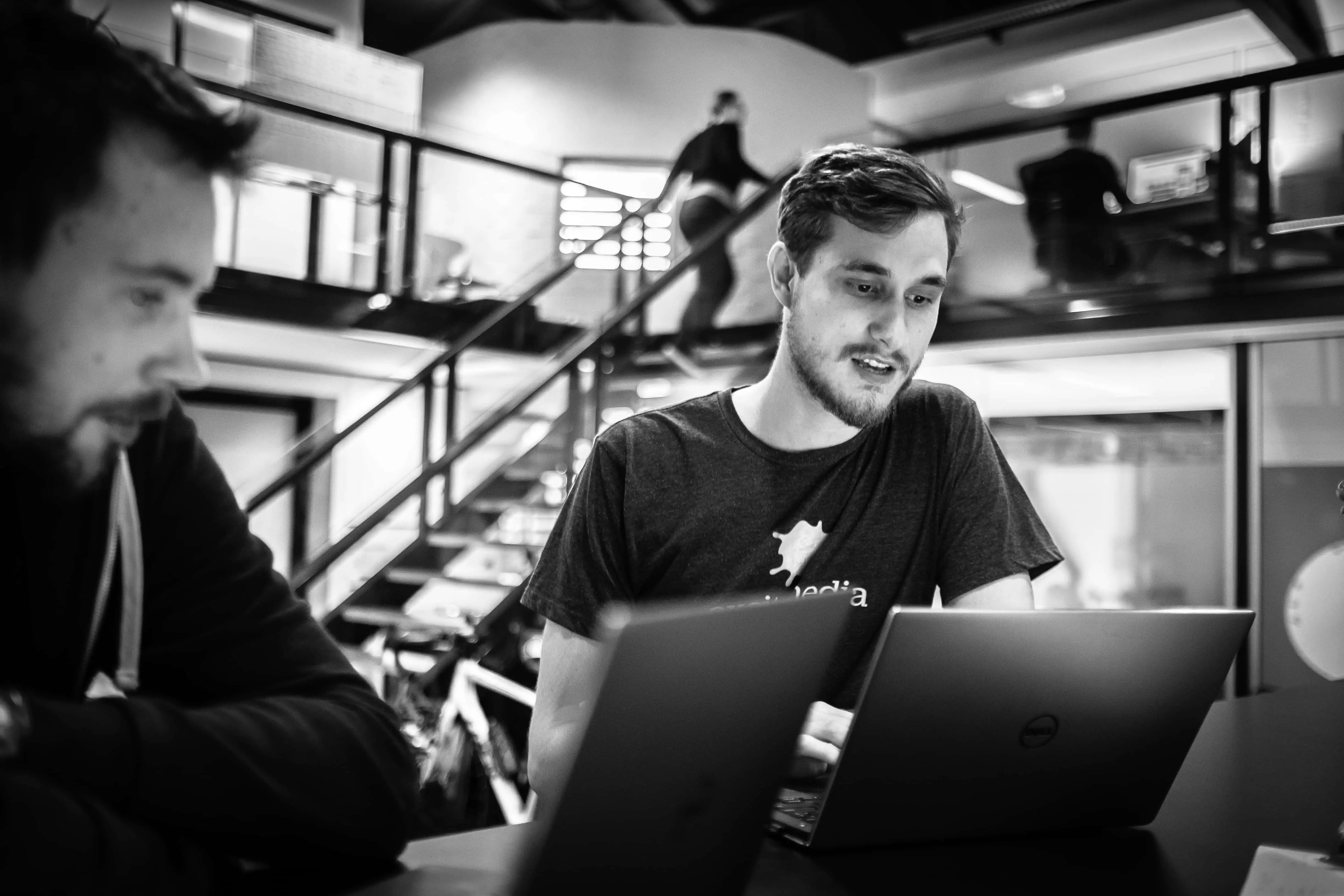 excite media employees discussing in front of a laptop