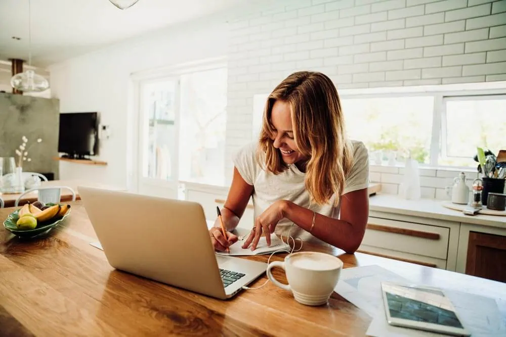 woman writing blog on kitchen counter