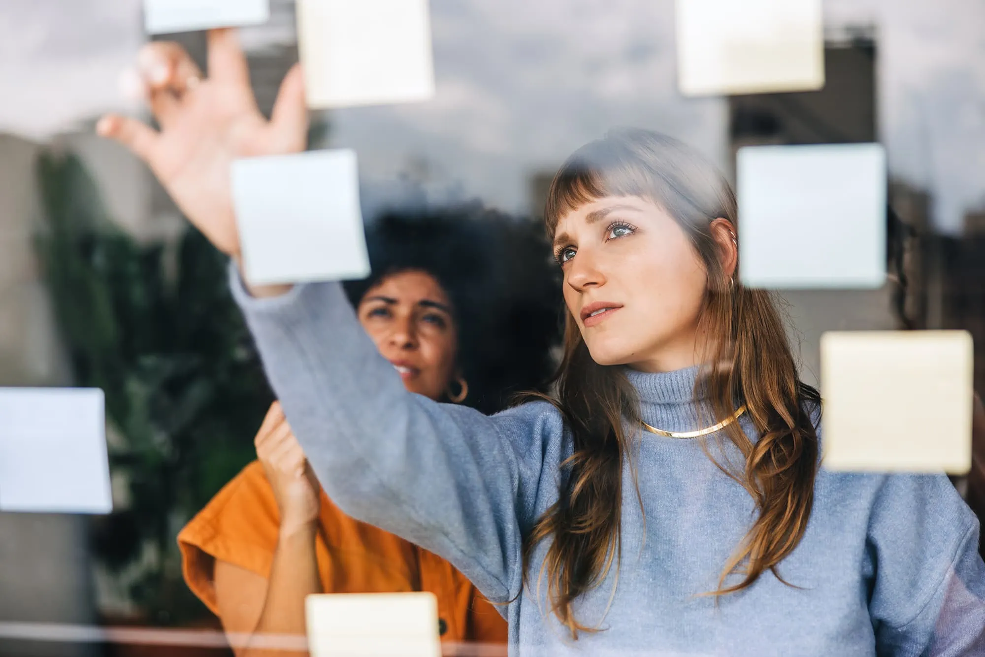 woman putting sticky notes on glass