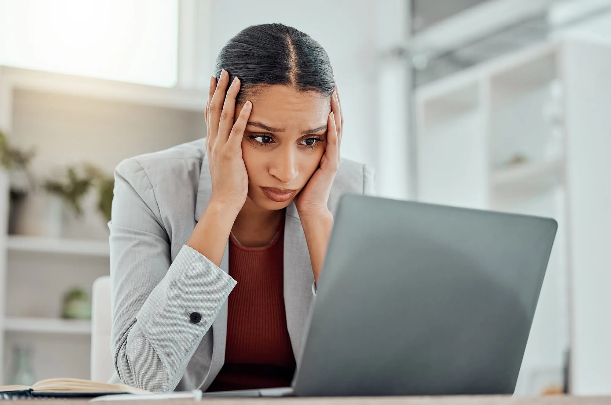 Pain, headache and stressed finance manager feeling sick, tired and worried about a financial problem at her startup company. Young and frustrated professional businesswoman working at an office